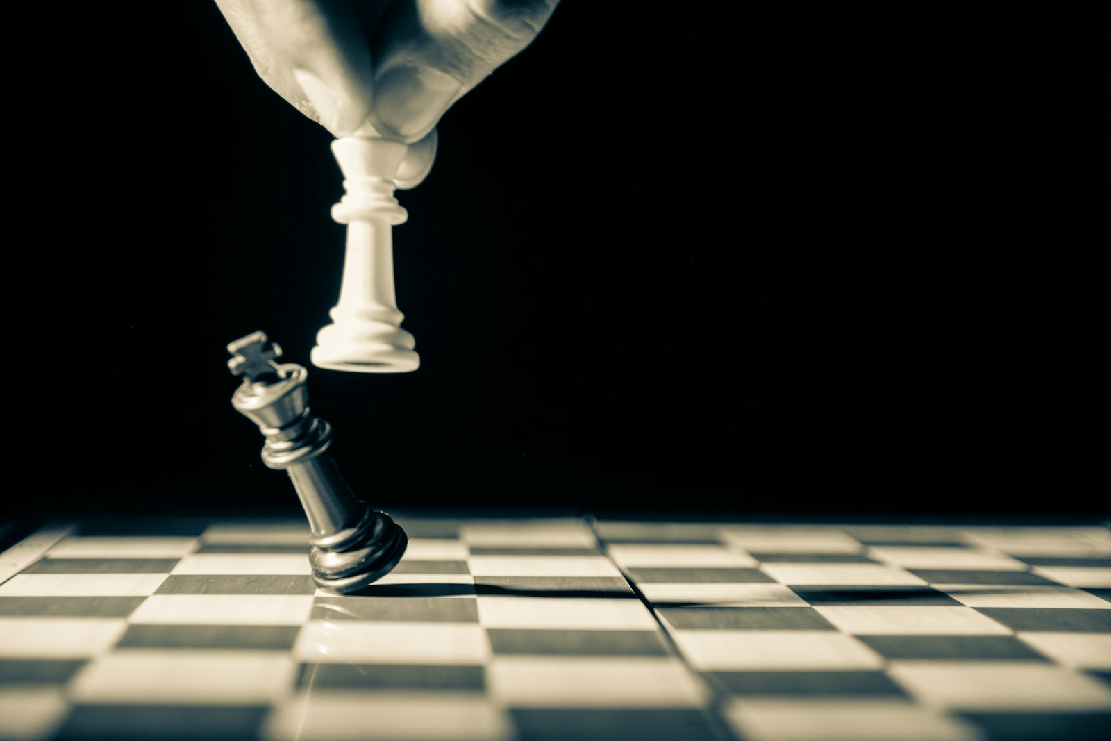 A chess king toppled beneath a standing piece